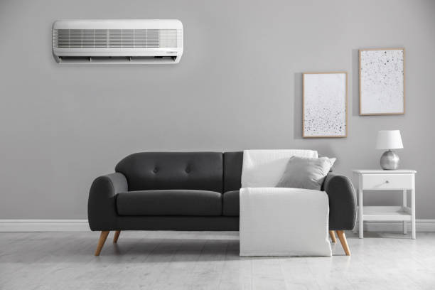 istock Modern air conditioner on light grey wall in room with stylish sofa 1464462596
