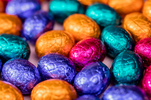 Big pile of colorful wrapped chocolate easter eggs, shiny festive Easter concept, Happy easter close-up candy sweets concept macro various colors