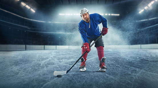 Hockey player on ice rink in sport arena field - stadium. Ready to shoot goal.
