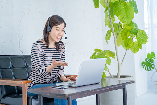 Woman working from home with headset and video chatting.