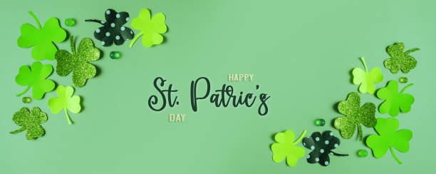 istock Happy St. Patrick's Day greeting text. Paper clover leaves on colored background banner format 1464472688