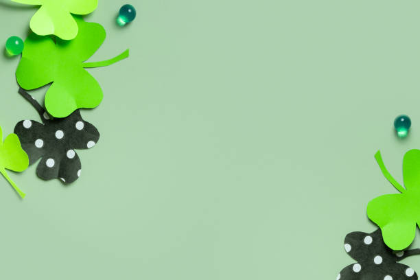 istock St. Patrick's Day minimalistic background. Paper clover leaves on colored background with copy space 1464472816