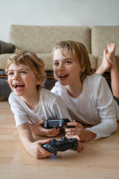 istock Cute children joyful playing video games with controller console, brother sister expressing emotions while enjoying their hobby playstation joystick. Vertical 1464479369