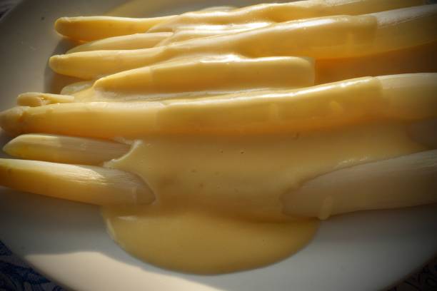 White asparagus with Hollandaise sauce. Boiled white asparagus with Hollandaise sauce on a plate. asparagus es un género de plantas con flores perteneciente a la familia asparagaceae, subfamilia asparagoideae. comprende hasta 300 especies. la mayoría son plantas perennes de hoja perenne de larga vida que crecen desde el sotobosque como lianas, arbust