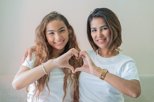 mother and daughter making heart symbols.