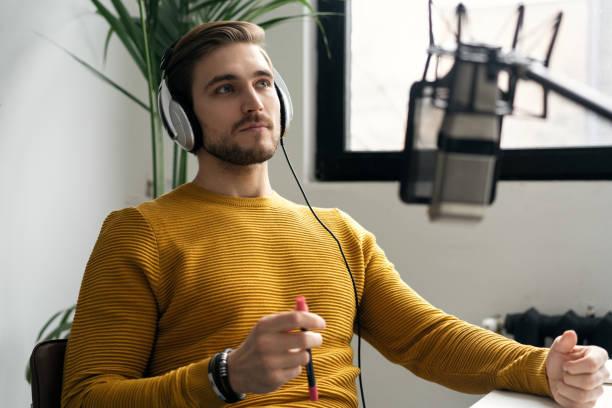 istock Man blogger smiling while broadcasting his live audio podcast in studio using headphones, laptop and headphones 1464484561