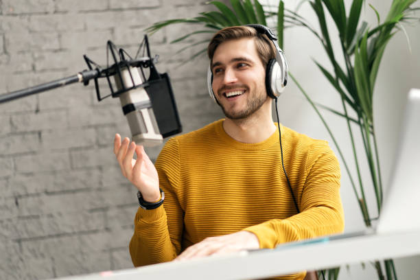 istock Man blogger smiling while broadcasting his live audio podcast in studio using headphones, laptop and headphones 1464484591