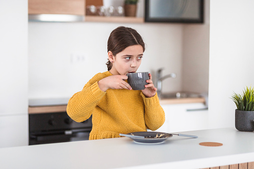 Young girl having breakfast and a hot beverage