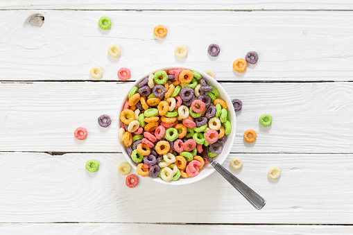 Colored breakfast cereals laid out in a bowl on a white wooden background, top view, children's healthy breakfast.