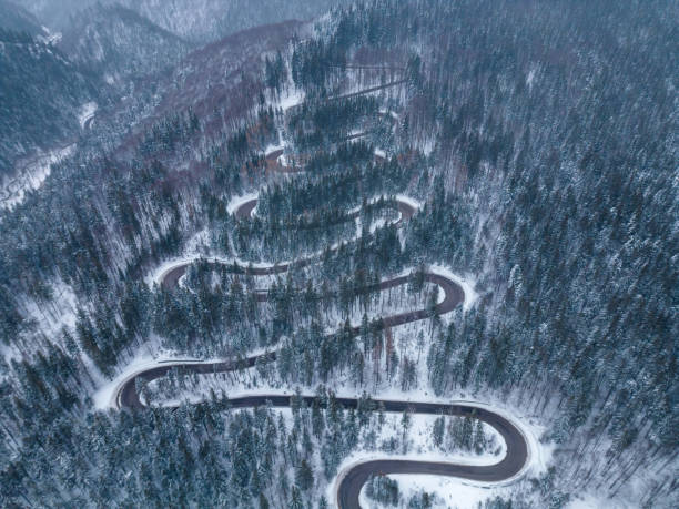 vista aérea de arriba hacia abajo de la carretera sinuosa de invierno en el bosque, transilvania, rumania. - road winding road mountain spiral staircase fotografías e imágenes de stock