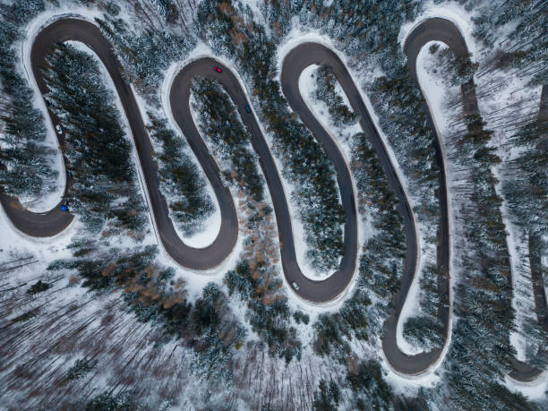 vista aérea de arriba hacia abajo de la carretera sinuosa de invierno en el bosque, transilvania, rumania. - road winding road mountain spiral staircase fotografías e imágenes de stock