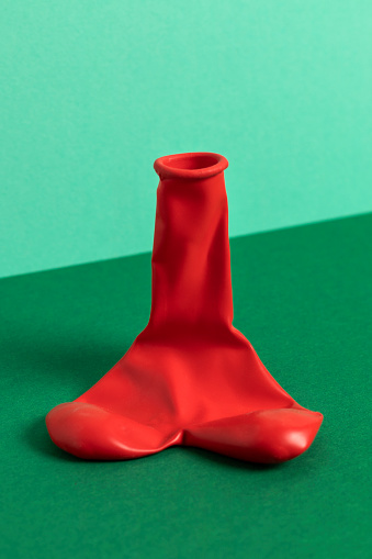 Deflated red balloon. The shape of penis, male potency concept.