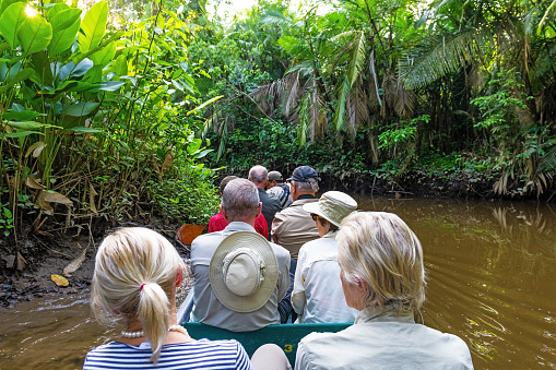 Group of people on wildlife canoe trip in Amazon rainforest, tourists looking for animals.