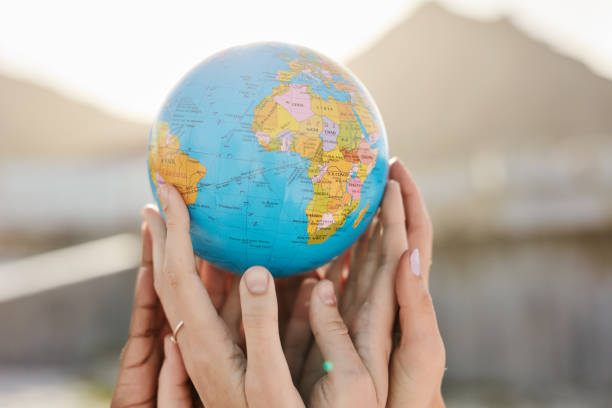 istock Community, Earth day or hands with globe or planet standing together as a group with global goals. Collaboration, team work or people in partnership with empathy, support or hope outdoors in nature 1464504405