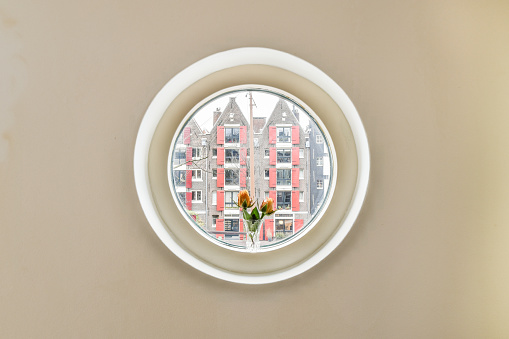 a round window with a flower in it's center and the view of an urban city from inside is visible