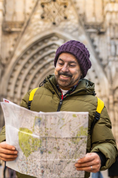 Smiling man on vacation consulting a map in the city.
