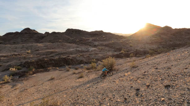 砂漠の道沿いの成熟した女性のマウンテンバイク - 5599 ストックフォトと画像