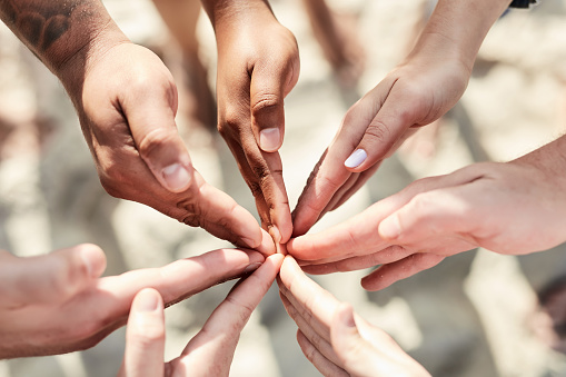 Solidarity, connected and hands in a circle together for support, trust and community diversity. Multiracial, partnership and hand of people touching for connection, teamwork and love in a shape.
