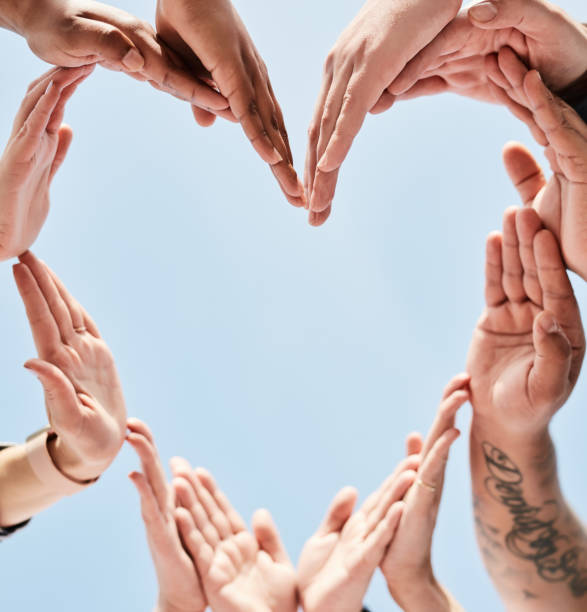 istock People, hands and unity forming heart in support, collaboration or teamwork below a blue sky background. Hand of group touching in hearty shape love symbol in trust, community or team synergy outside 1464510032
