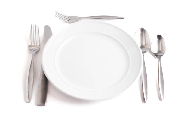 Empty white plate and fork,spoon and table knife on white plate