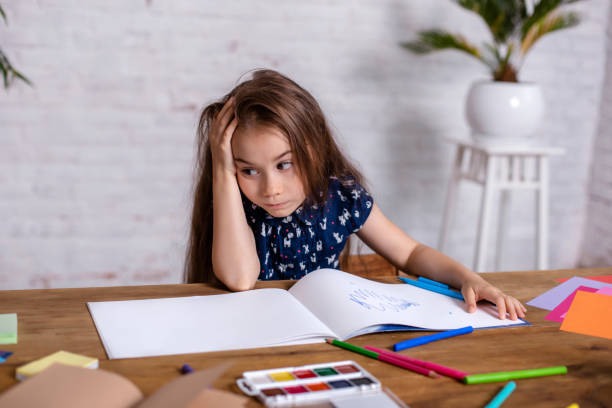 istock Thoughtful little girl at the table draw with crayons 1464515254