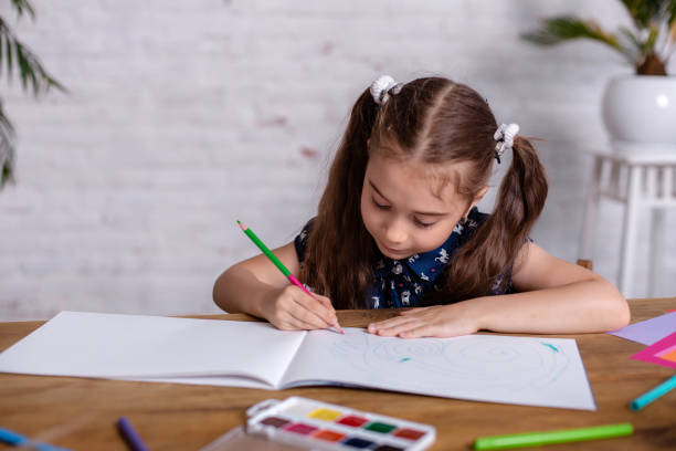 istock Inspired little girl at the table draw with crayons or do home work 1464517273
