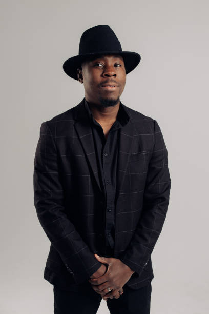 istock Young african man in suit and hat stands against gray background. 1464520390