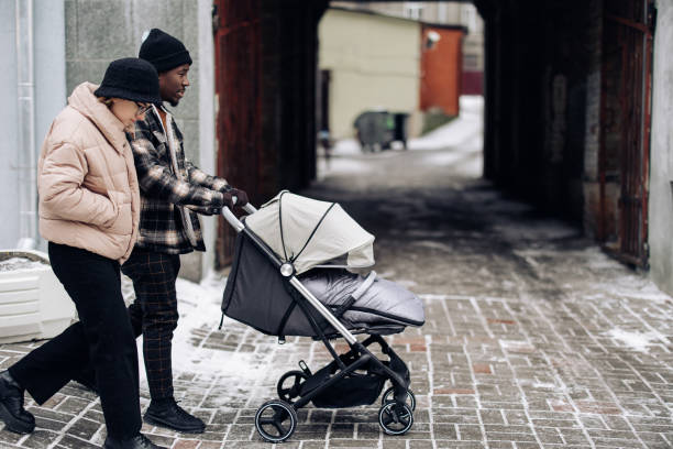 Happy interracial family walk on street and push baby carriage. Happy interracial family walk on street and push baby carriage. Concept of interracial family and unity between different human races. baby stroller winter stock pictures, royalty-free photos & images