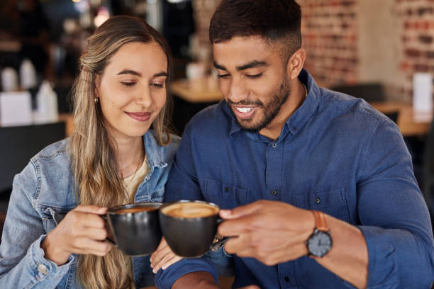 istock Interracial couple, cafe and toast coffee cup for celebration, anniversary or congratulations for relationship. Man, woman and celebrate at restaurant with cappuccino with love, smile and happiness 1464523778