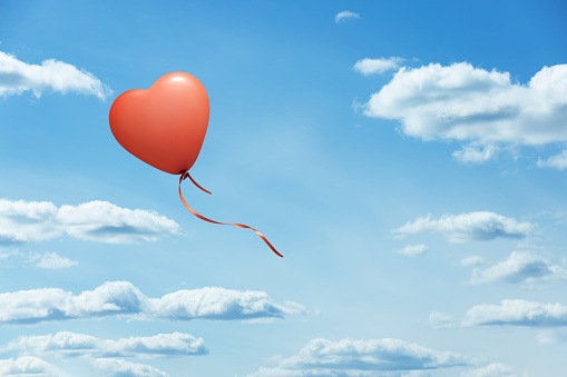 Heart shaped red balloon on blue sky. This file is cleaned and retouched.