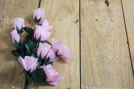 Plastic roses on top of a wooden background