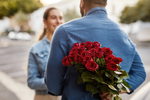 Man, hiding roses and surprise gift for partner in city with romance, relationship and anniversary. Secret flower bouquet, couple and valentines day present with love, care and outdoor date together