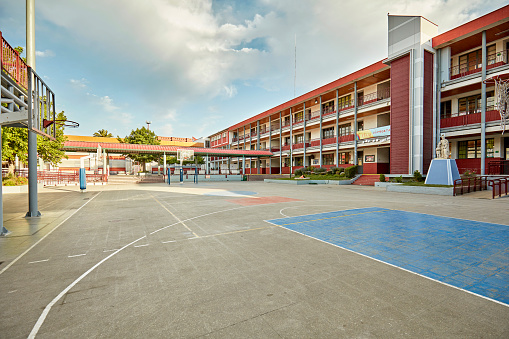 Wide angle view of three-story elementary school building and sports court for recreation.
