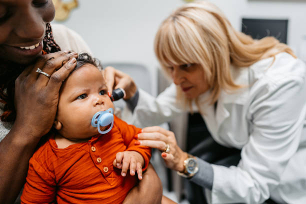 Young Female Pediatrician Examining A Newborn Baby Boy Young black female pediatrician examining a newborn baby boy at the pediatric clinic. ear horn photos stock pictures, royalty-free photos & images