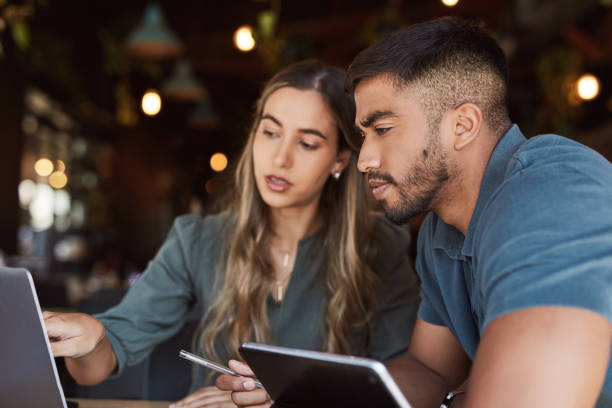 istock Thinking business people, technology or planning in cafe collaboration on website branding, logo or digital marketing. Man, woman or teamwork pointing at laptop or tablet in remote working restaurant 1464536821