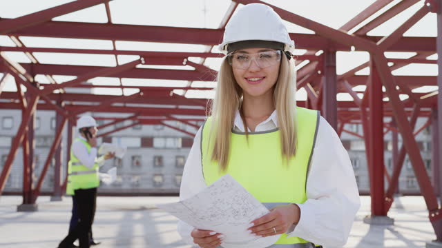 Young female contractor in hardhat smiles looking in camera