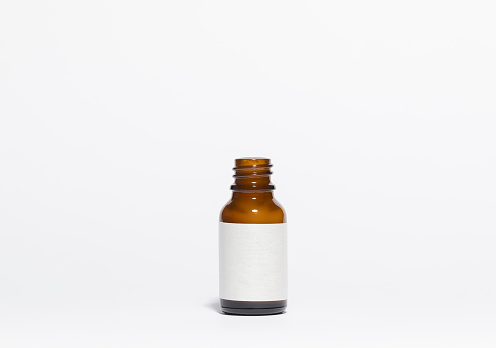 Mockup of open amber colored glass bottle of cosmetic and facial care products, on a white background