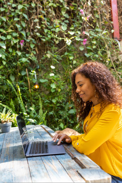 istock Side view of Bazilian woman using laptop at garden 1464542607