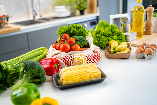 Close up of Eco friendly mesh shop bag full of raw organic fruits and vegetables on kitchen counter. High resolution 42Mp indoors digital capture taken with SONY A7rII and Zeiss Batis 40mm F2.0 CF lens