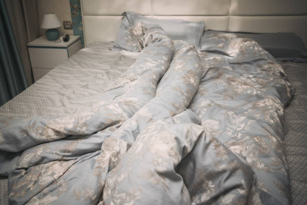 Crumpled bed linen blanket and pillows is messy lie about in bedroom or hotel room at morning.