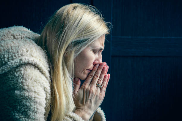 mujer de mediana edad en oración llorosa - confession booth fotografías e imágenes de stock