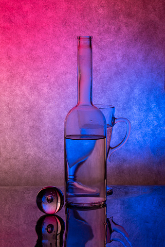 Still life with glassware with liquid on a red-blue background