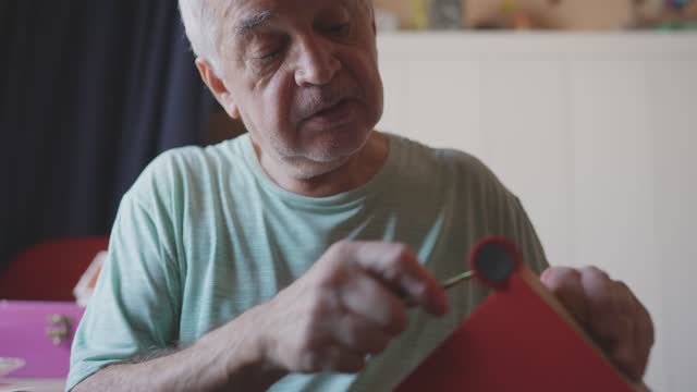 Senior man painting a piece of wood at home