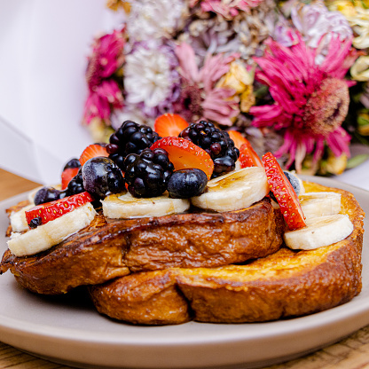 French toast with fruit slices and flowers in background