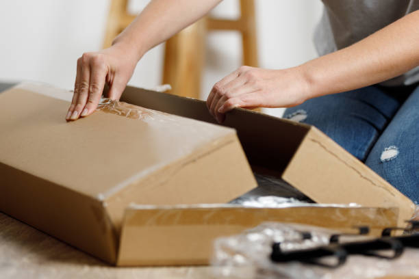 istock A woman opens a box with goods delivered by mail to her home. 1464552588