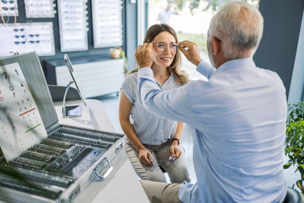 istock Senior optometrist helping client trying on some glasses 1464554636