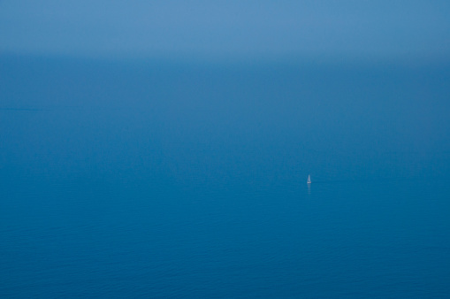 A sailboat drifts off the coast of Cinque Terre in Italy on a beautiful sunny Summer's Day