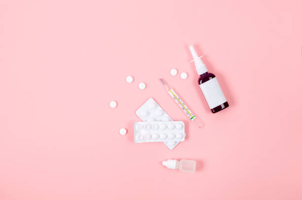 istock Pink background with pills, thermometer, spray bottles, blister, flat lay. 1464560198