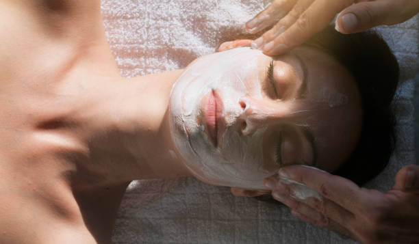 Skillful beautician cleaning and touching female face