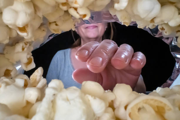 Woman is eating popcorn, view from the package